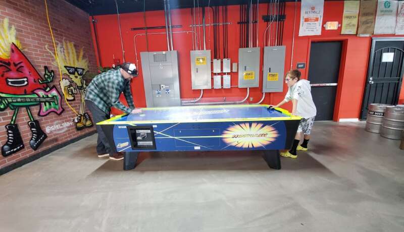 Guests playing air hockey at Bay Boys Brewing, enjoying a fun and fast-paced game.